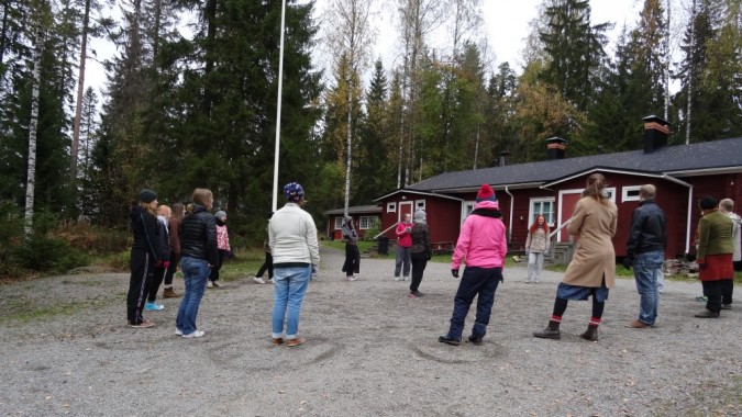 Osallistujia ringissä ulkona ja yksi on keskellä.