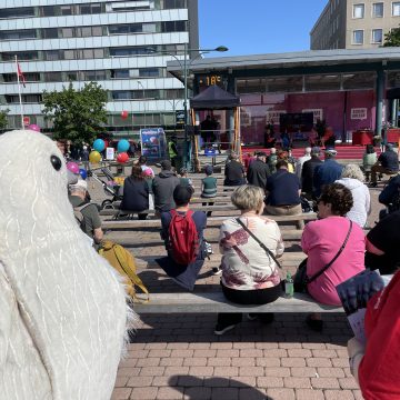 Rauhankyyhkypukuun pukeutunut vapaaehtoinen seuraa keskustelutilaisuutta SuomiAreena-tapahtumassa.