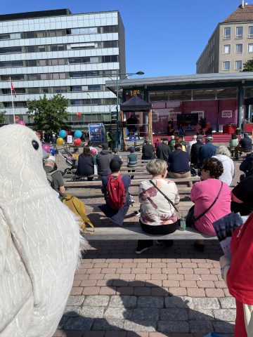 Rauhankyyhkypukuun pukeutunut vapaaehtoinen seuraa keskustelutilaisuutta SuomiAreena-tapahtumassa.