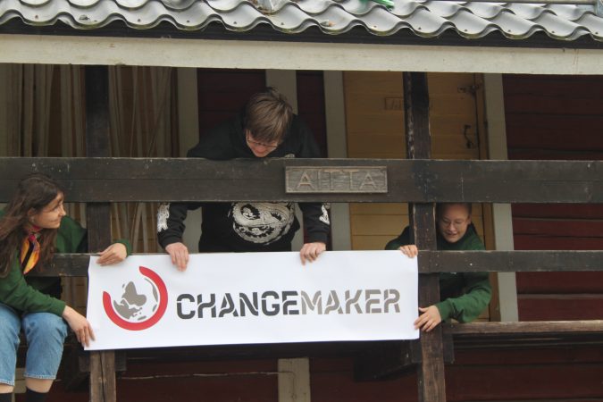 Changemaker-vapaaehtoiset nostamassa Changemaker-banneria aitan ylätasanteelle.