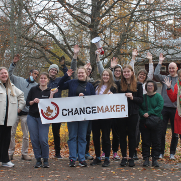 Changemaker-viikonlopun osallistujia Changemaker-kyltin kanssa