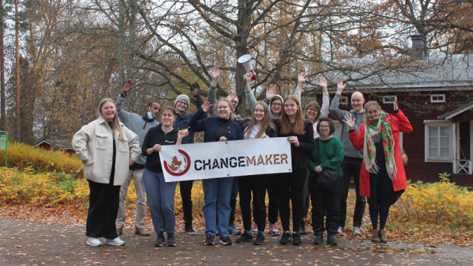 Changemaker-viikonlopun osallistujia Changemaker-kyltin kanssa