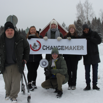 Changemakerin tiimiläisiä Changemaker-banderollin kanssa.