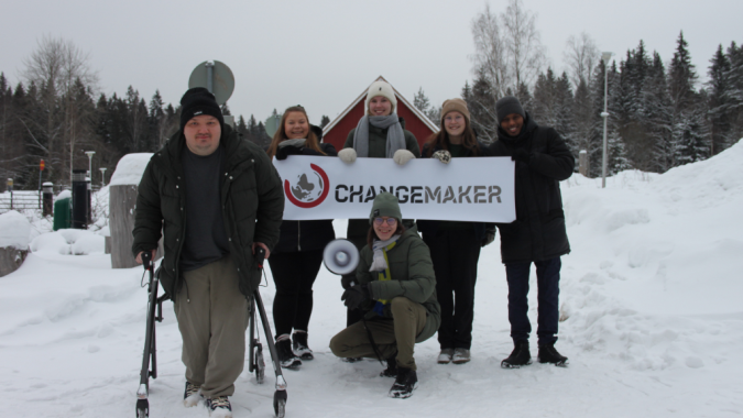 Changemakerin tiimiläisiä Changemaker-banderollin kanssa.