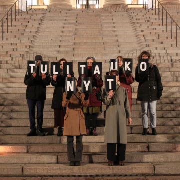 Mielenosoittajia Eduskuntatalon portailla kädessään kylttejä, joista muodostuu sanat "Tulitauko nyt".